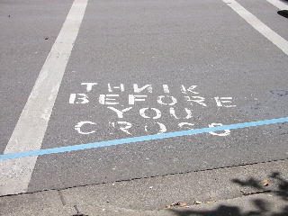 Painted on the road at a crosswalk: &lsquo;Thnik Before You Cross&rsquo;